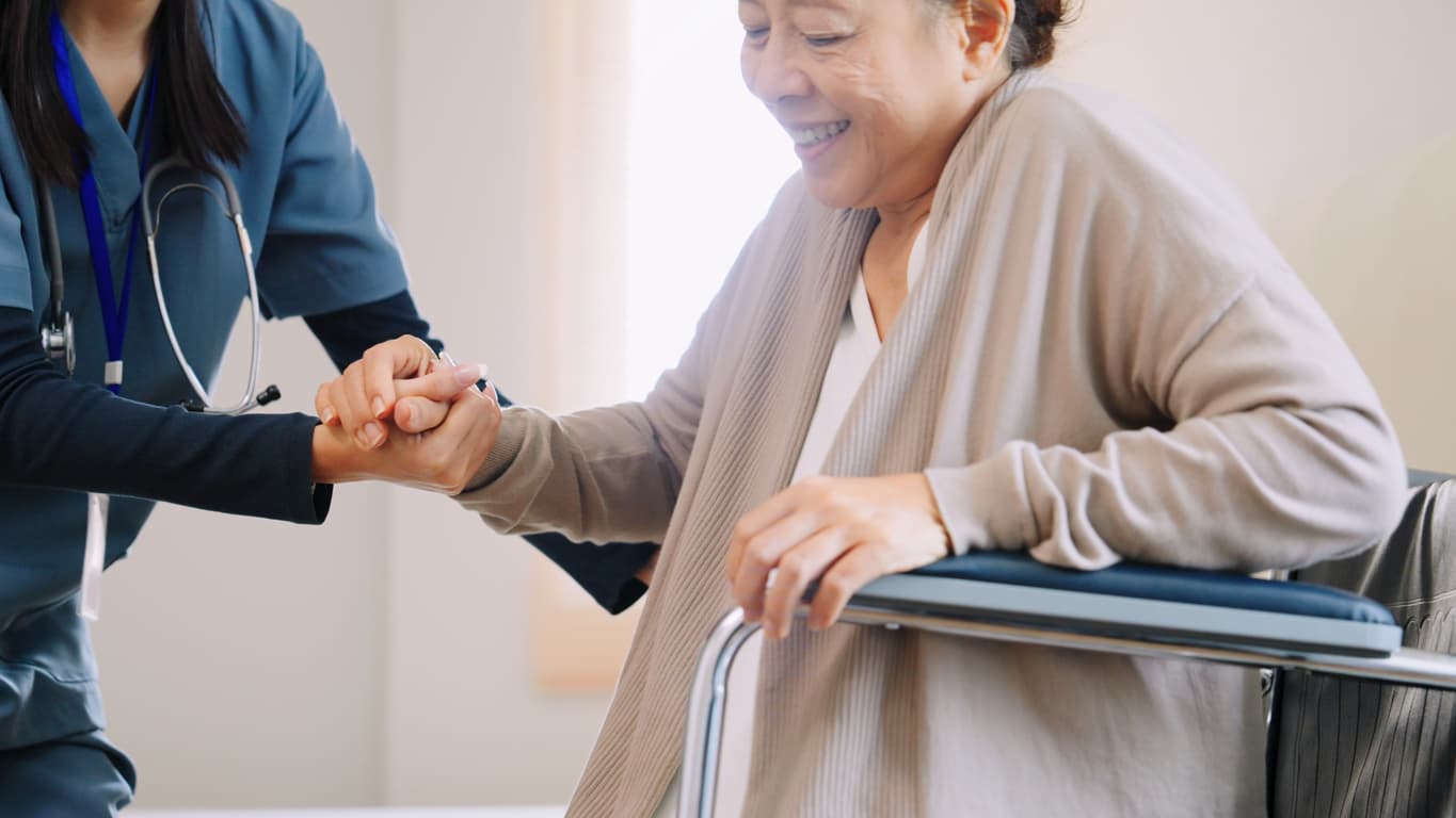 Healthcare professional helping woman in wheelchair