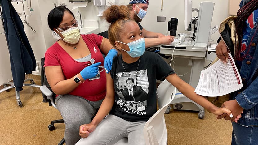 Teenager Maliyah Rather holds her mom's hand while gettig the first dose Pfizer's COVID-19 vaccine