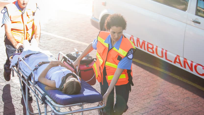 Paramedics wheeling patient in hospital parking lot