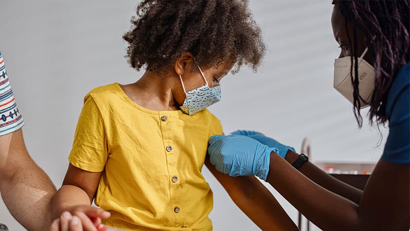 Pediatrician places a bandaid on a patient's arm during a check-up