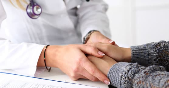 Image of caregiver holding patient's hands, supportive oncology