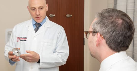 Ryan Merkow, MD, holding a hepatic artery infusion (HAI) device
