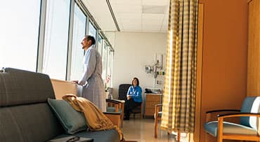 Patient standing in a waiting room looking out of a window