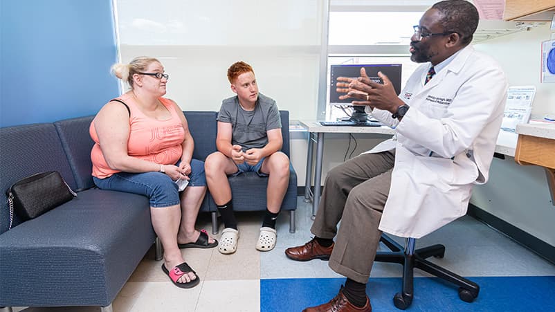 Dr. Timothy Sentongo meeting with pediatric patient and parent