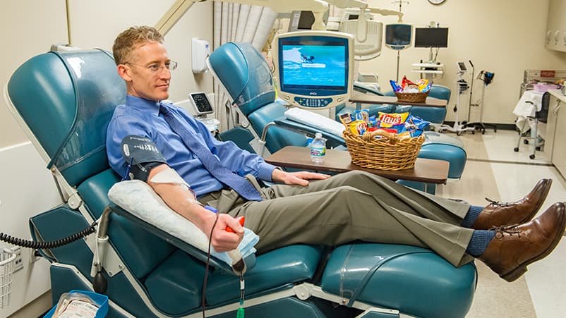 Doctor sitting on cabinet looking right, looking happy