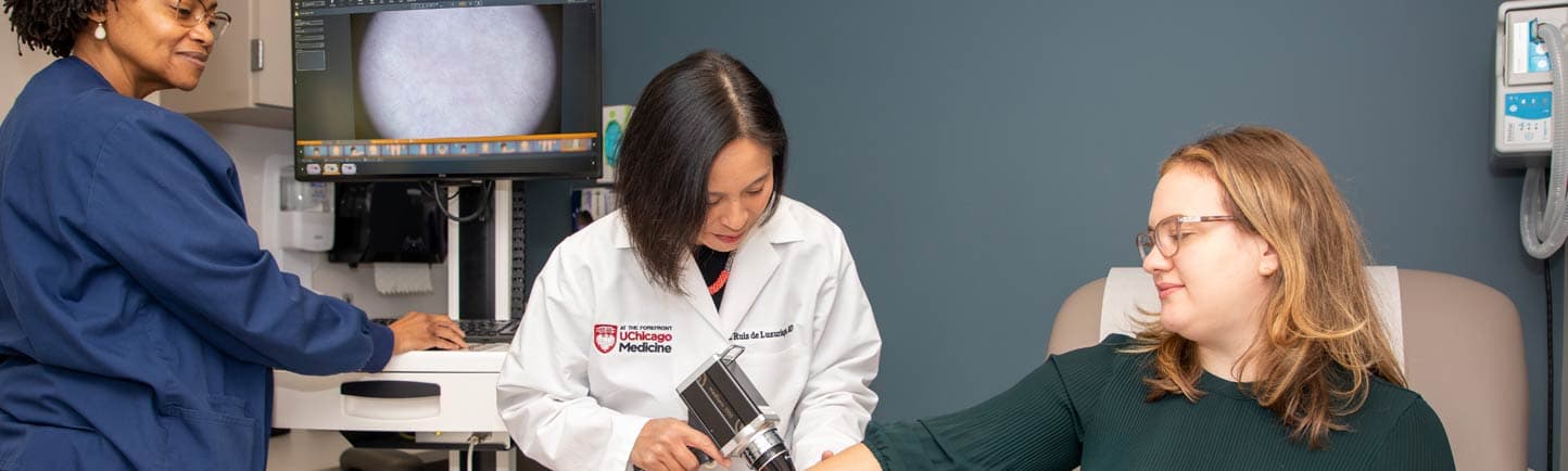 Dermatologist Arlene Ruiz De Luzuriaga, MD, MPH, MBA, examines a patient in clinic