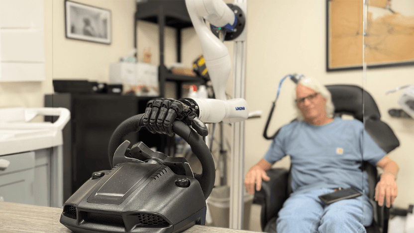 A testing participant controls a bionic hand through a brain-computer interface that allows him to feel pressure changes as the steering wheel moves in the hand.